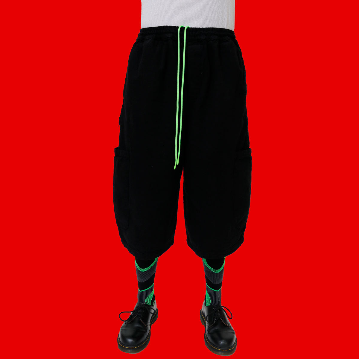 Black baggy pants with green drawstring on a red background