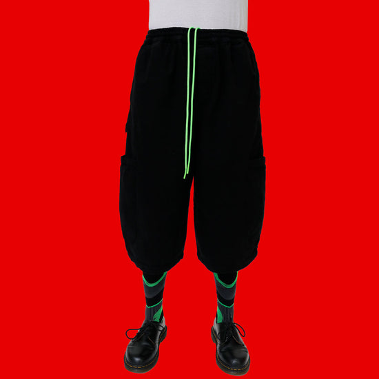 Black baggy pants with green drawstring on a red background